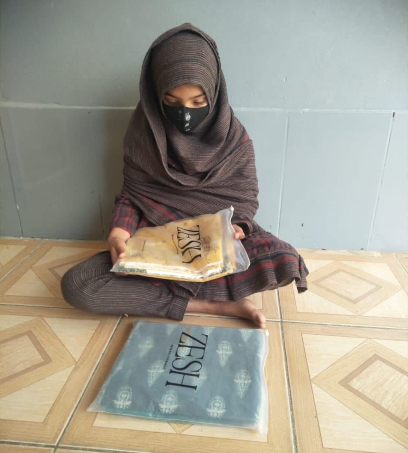 A girl holds a wrapped set of new clothes