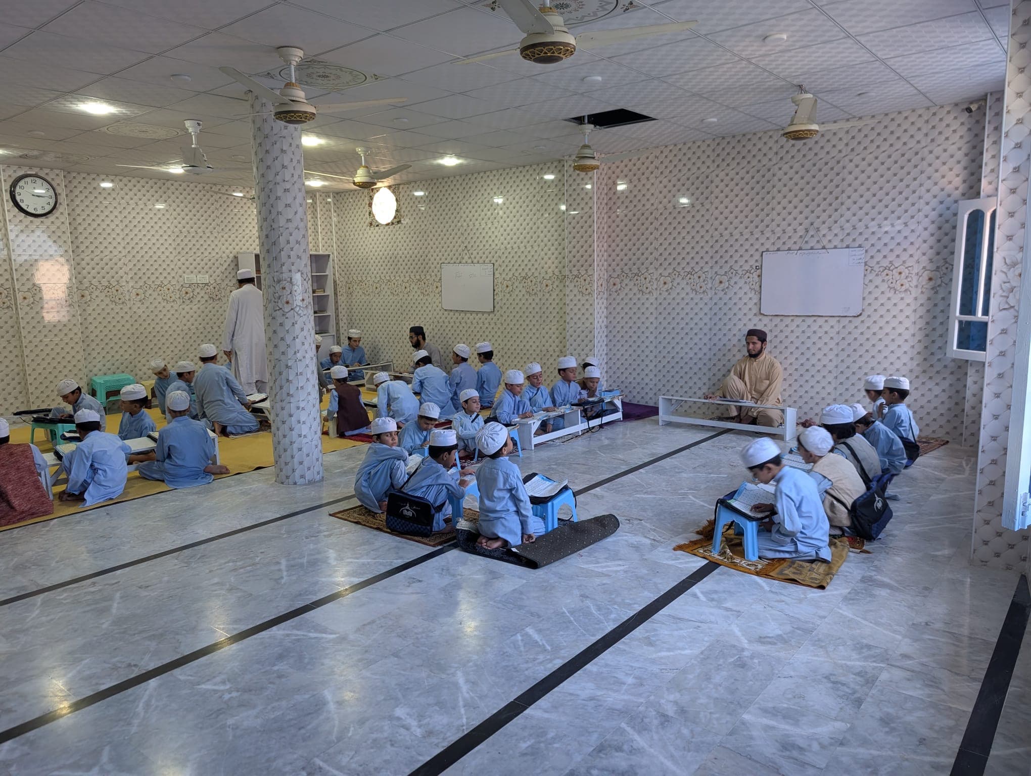 Rows of boys in blue uniforms study in a bright renovated classroom